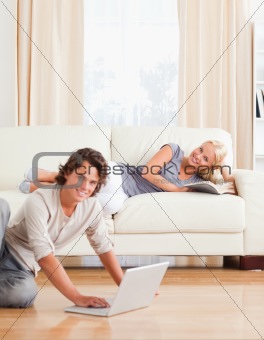 Portrait of a man with a laptop while his girlfriend is with a book