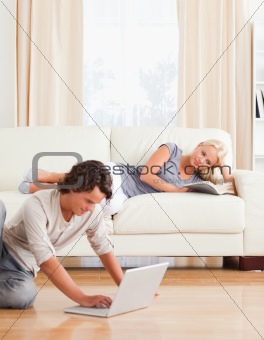 Portrait of a man using a laptop while his girlfriend is reading a book