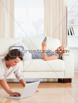 Portrait of a man using a laptop while his wife is reading a book