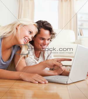 Close up of a couple using a notebook while lying on the floor