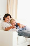 Portrait of a laughing couple cuddling while watching TV