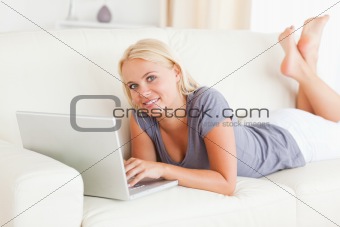 Lying blonde woman using a laptop