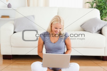 Happy woman using a notebook while sitting on the floor