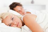 Woman looking at the camera while her fiance is sleeping