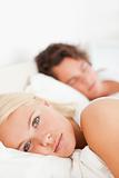 Portrait of a woman looking at the camera while her fiance is sleeping