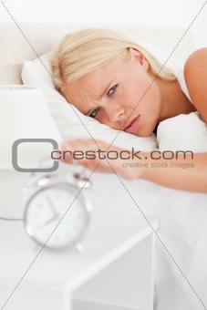 Portrait of a cute woman awaken by an alarmclock