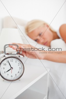 Portrait of an unhappy woman switching off her alarmclock