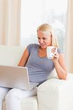 Portrait of a woman having a tea while using a laptop