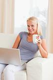 Portrait of a woman having a tea while holding a laptop