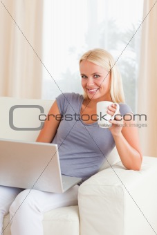 Portrait of a woman having a tea while holding a laptop
