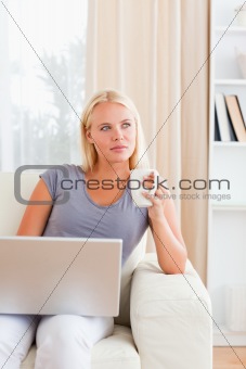 Portrait of a woman having a coffee while holding a laptop