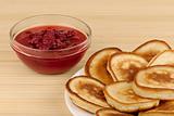 heap of pancakes with bowl of strawberry jam