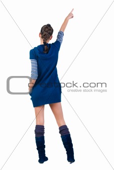 Beautiful young woman in dress pointing at wall. Rear view.