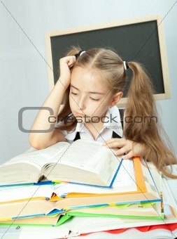 School girl making homework behind stack of books.