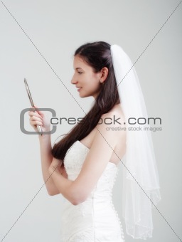 portrait of a bride with long dark hair in wedding dress - isolated on gray