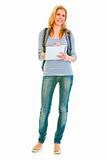 Full length portrait of smiling teen girl with schoolbag writing in notebook
