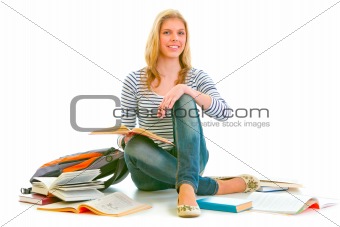 Cheerful teen girl sitting on floor among schoolbooks
