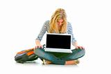 Teen girl sitting on floor and looking on laptops blank screen
