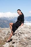 woman in black dress sitting on a rock
