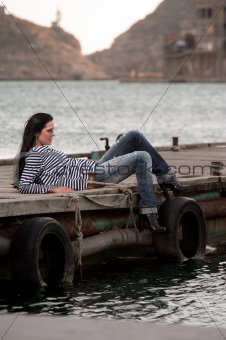 woman lying on a pier in the background of the sea