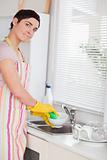 Woman washing the dishes looking into the camera