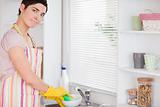 Brunette Woman washing the dishes looking into the camera