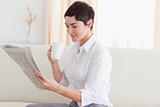 Woman with a cup reading the news
