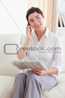 Brunette Woman with a cellphone and a newspaper