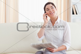 Cheerful Woman with a cellphone and a newspaper