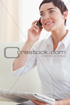 Close up of a cute woman with a phone and a newspaper