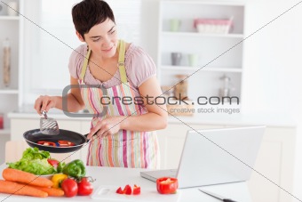Beautiful woman cooking with receipt on laptop
