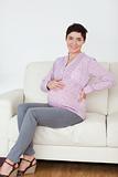 Smiling pregnant woman sitting on a sofa