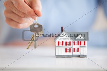 Woman holding keys next to a model house