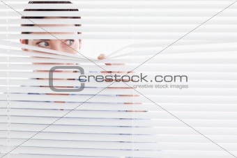 Curious businesswoman peeking out of a window