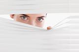 Brunette businesswoman peeking through a venetian blind