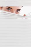 Businesswoman peeking through a venetian blind