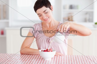 Woman pouring cream over strawberries