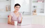 Gorgeous Woman working with a laptop holding a cup