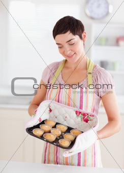 Smiling brunette woman showing muffins
