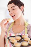 Smiling brunette woman showing muffins while eating one