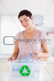 Charming brunette Woman putting bottles in a recycling box