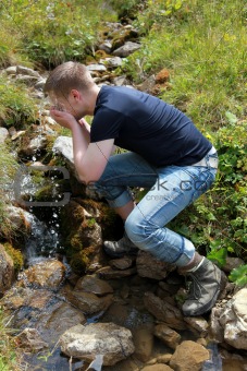 Young man taking a refreshment in the mountains
