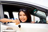 young happy woman in car showing the key