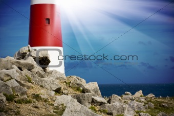 Lighthouse on rocks with light beams