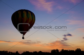 Hot-air balloon floating against a reddish dawn sky