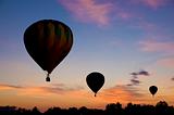 Hot-air balloons floating against a reddish dawn sky