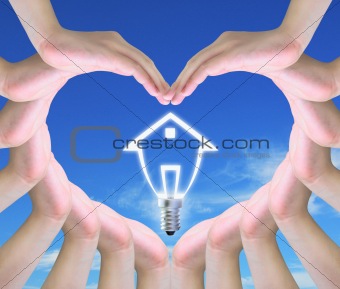 light bulb model of a house in women hands making a symbol of love