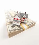Small House on Row of Hundred Dollar Bill Stacks Isolated on a White Background.