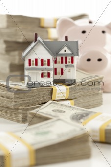 Small House and Piggy Bank with Stacks of Hundred Dollar Bills Isolated on a White Background.