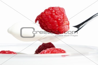 closeup of a raspberry on a spoon with yogurt